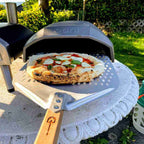 Pizzaschaufel vor Ooni Ofen mit Pizza