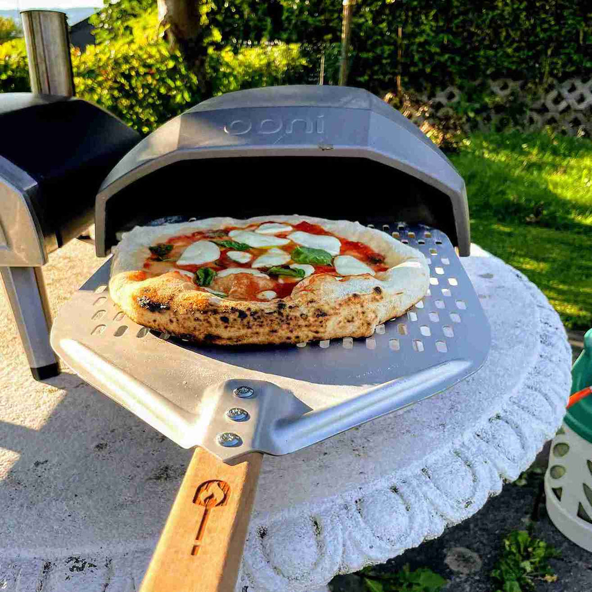 Pizzaschaufel vor Ooni Ofen mit Pizza